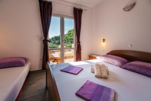 1 Schlafzimmer mit 2 Betten mit violetter Bettwäsche und einem Fenster in der Unterkunft Apartments Pitarević in Saplunara