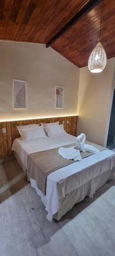 a bedroom with two beds and a chandelier at Pousada Lua Nova Charmosa Pipa in Pipa