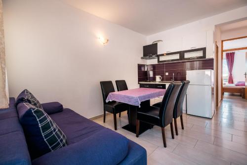 ein Wohnzimmer mit einem Tisch und einem lila Sofa in der Unterkunft Apartments Pitarević in Saplunara