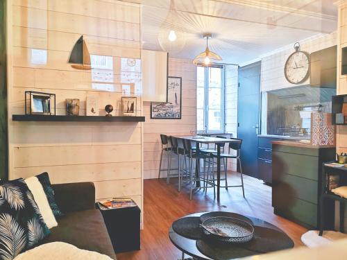 uma sala de estar e cozinha com um sofá e uma mesa em Au cœur des remparts, L'ÉCRIN Appartement 2 chambres pour 2-6 pers em Saint Malo