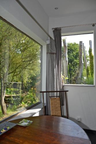 une salle à manger avec une table et une grande fenêtre dans l'établissement Chambres d'hôtes, Gîtes La Petite Madeleine, à La Madelaine-sous-Montreuil