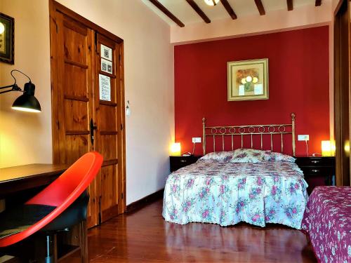 a bedroom with a bed and a red wall at Casa Bracamonte in Mondoñedo