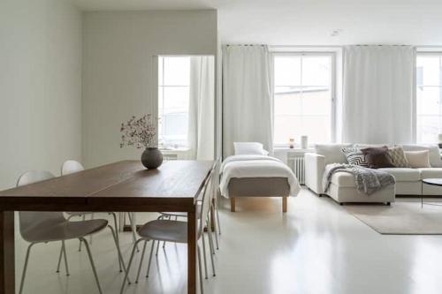 una sala de estar blanca con mesa y sillas en Spacious and central apartment with private sauna, en Helsinki