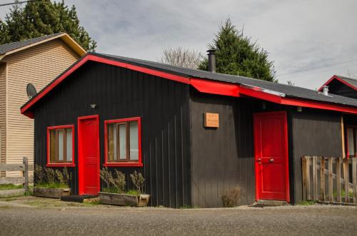 una casa negra y roja con puertas rojas en Refugio Simple Sur Casa 4 - 5 personas, en Malalcahuello