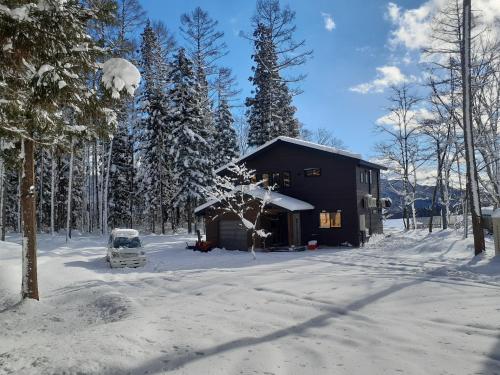 une cabine dans la neige avec une camionnette devant dans l'établissement Hakuba Kaede House, à Hakuba