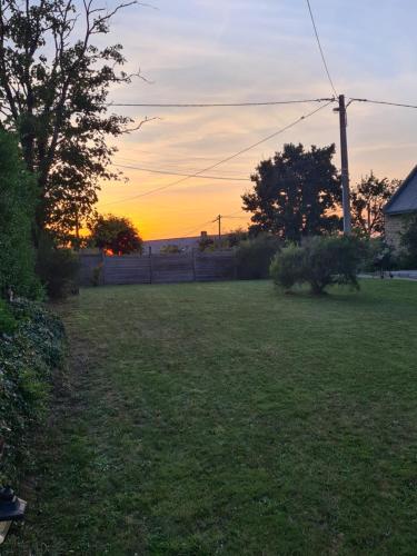 a sunset in a yard with a field of grass at Gîte Avalon - Closeries du Golfe in Theix