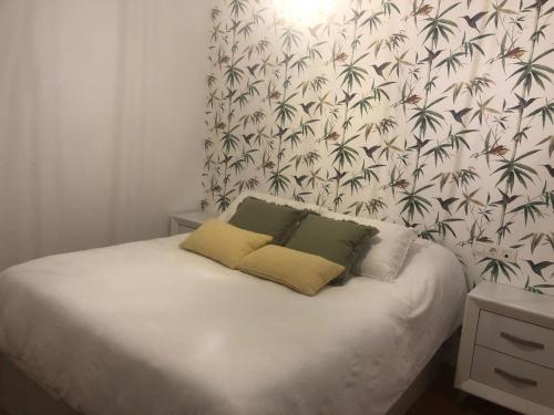 1 cama con 2 almohadas en un dormitorio con papel pintado en Granada-Cogollos Vega Village, en Cogollos De La Vega