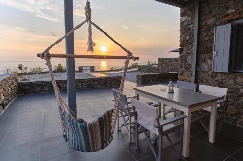 eine Veranda mit Hängematte, Tisch und Stühlen in der Unterkunft Cape Suites in Kythnos