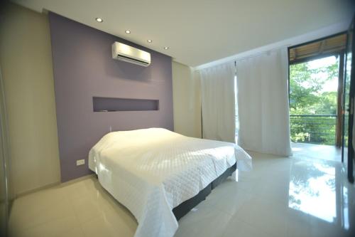 a bedroom with a white bed and a balcony at Tekoa Lodge in Puerto Iguazú