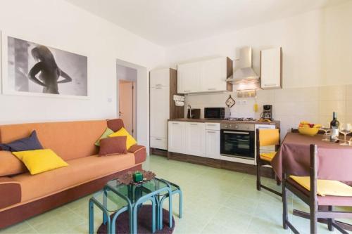 ein Wohnzimmer mit einem Sofa und einem Tisch sowie eine Küche in der Unterkunft Two Bedroom Apartment Valdebecco for 5 persons in Pula