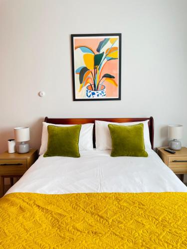 a bedroom with a white bed with green pillows at Rooms At The Rosebery in Norwich