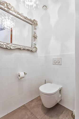 a white bathroom with a toilet and a mirror at Landgoed Hermitage - Villa Minerva - XXL Zwemspa - max 16 personen in Ouddorp