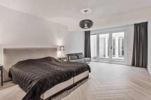 a bedroom with a large bed and a couch at Landgoed Hermitage - Villa Minerva - XXL Zwemspa - max 16 personen in Ouddorp