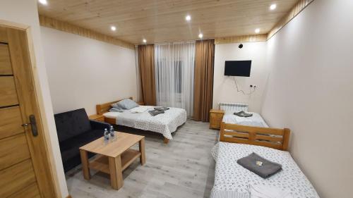 Cette petite chambre comprend deux lits et une table. dans l'établissement Wyspa Mszanka, à Mszana Dolna