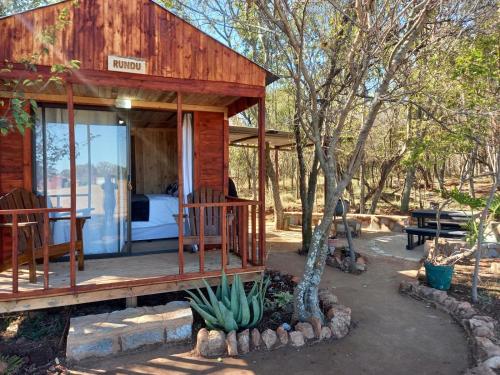 a wooden cabin with a bed and a table and chairs at FLY FISHING PARADISE ON THE VAAL in Parys