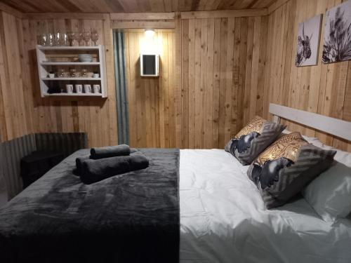 a bedroom with a large white bed with wooden walls at FLY FISHING PARADISE ON THE VAAL in Parys