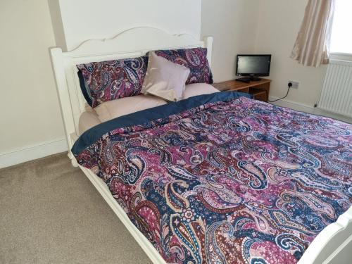 a bedroom with a bed with a colorful blanket at Croydon - Compton in South Norwood