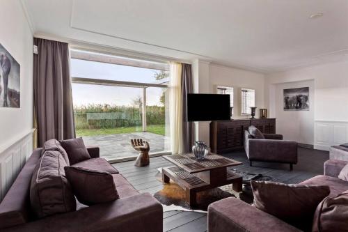 a living room with a couch and a tv at Landgoed Hermitage - Villa Euphoria - XXL Zwemspa - Max 10 personen in Ouddorp
