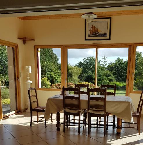 une salle à manger avec une table, des chaises et des fenêtres dans l'établissement Les Korrigans, à Tréméven