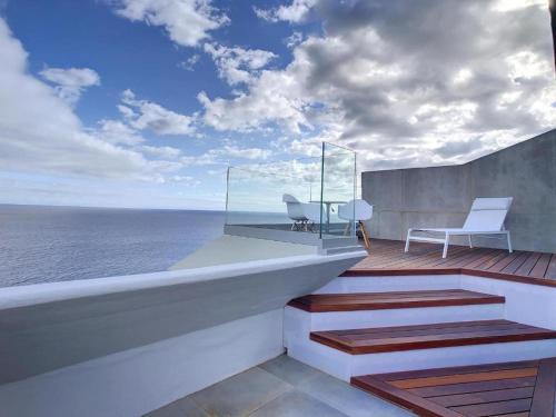 a balcony with a desk and chair on the ocean at Luxurious Penthouse Suite direct at sea in Caniço
