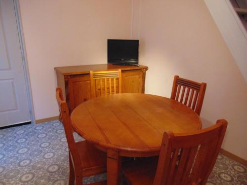 une table en bois avec des chaises et une télévision sur une armoire dans l'établissement Maison Hélie, à Avignon