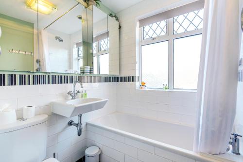 a bathroom with a sink and a tub and a mirror at Bishy Road Hideaway near York Racecourse in York