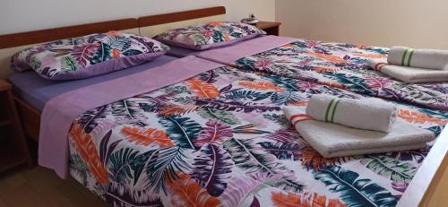 a bed with a colorful comforter and pillows on it at Apartments Kornati in Ždrelac