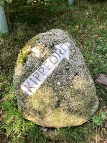 a rock with a sign on it on the grass at Kipplochan in Dalbeattie
