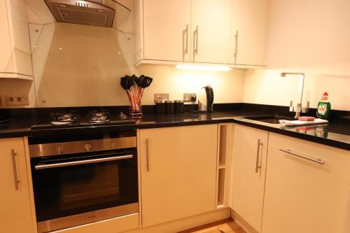 a kitchen with white cabinets and black counter tops at Clifton Studio in Bristol