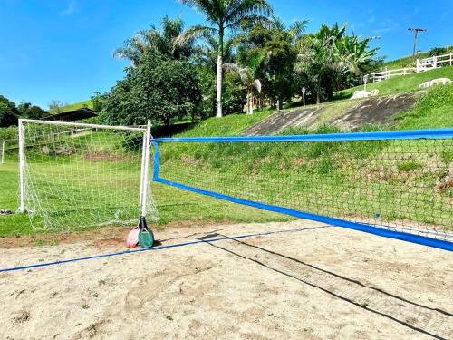 a volleyball net on a sandy field with palm trees at Pousada Sonho Meu in Itanhandu