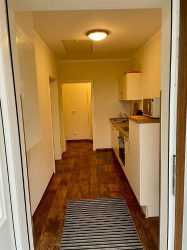 a kitchen with white cabinets and a wooden floor at Lindenhaus Scharfe Kurve in Rosenow