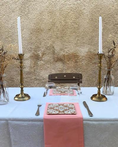 a table with two candles on top of it with a table with a pink table at Masseria Fontana di Vite in Matera