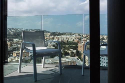 two chairs on a balcony with a view of a city at InterContinental Malta by IHG in St Julian's