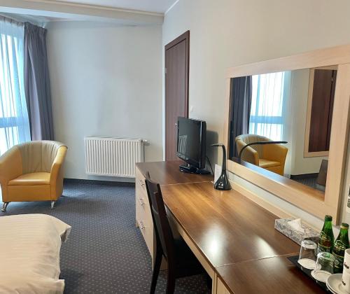 a hotel room with a desk with a television and a mirror at Poleczki Residence Apartments in Warsaw