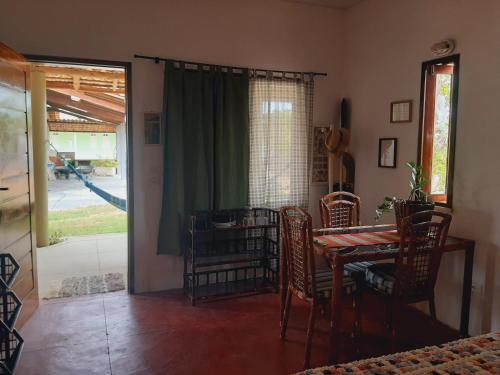 a dining room with a table and chairs and a sliding glass door at CHALE PERTO DA PRAIA COM DUAS SUITES E VARANDAO in Pacatuba