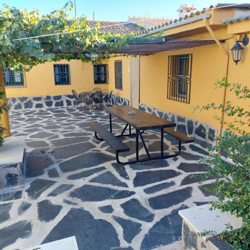 a patio with a wooden table and a bench at Casa Labradores Piscina, SPA, Barbacoa y Salon Juegos in Camarenilla