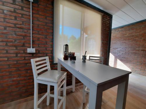 a white table and chairs in a room with a brick wall at Ocaso Apart Andino in Andino