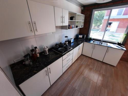 a kitchen with white cabinets and a black counter top at Ocaso Apart Andino in Andino