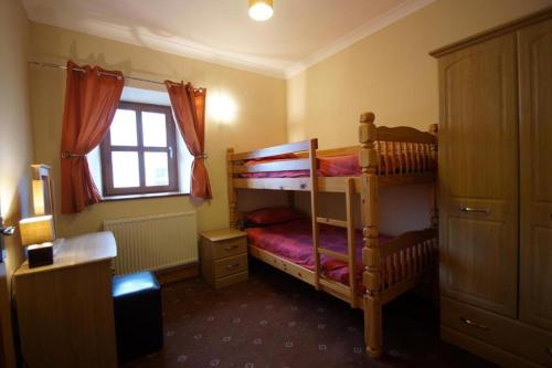 a bedroom with two bunk beds and a window at Blaengader Cottages - Enlli in Aberystwyth