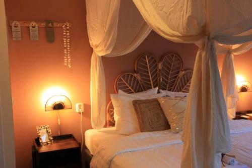 ein Schlafzimmer mit einem Himmelbett und weißen Kissen in der Unterkunft Maison Bellefleur B&B - Pension in Renesse
