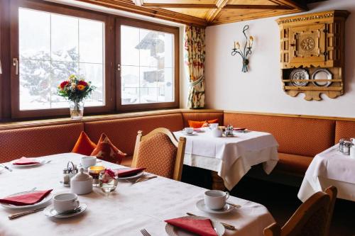 a dining room with two tables and two windows at Hotel Kristall in Lech am Arlberg