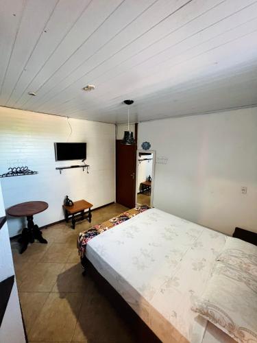 a bedroom with a large bed and a tv at Pousada Rosa Center in Praia do Rosa