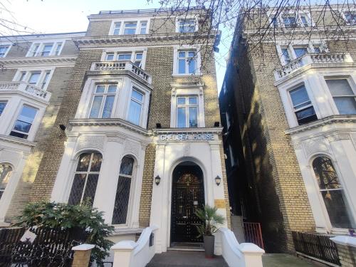 een groot bakstenen gebouw met een zwarte deur bij Chelsea House Hotel - B&B in Londen