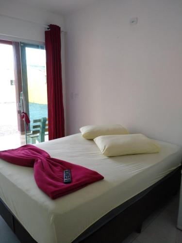a bed with a red robe sitting on top of it at Residencial Alexandre - Com piscina aquecida in Matinhos