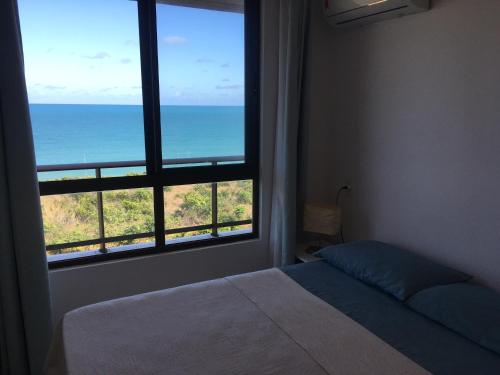a bedroom with a view of the ocean from a window at Praia Bela, vista mar. Novo! in Pitimbu