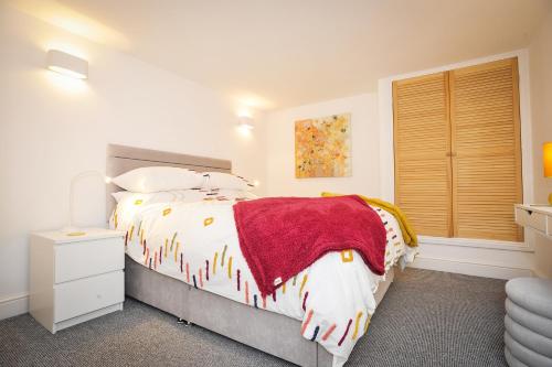 a bedroom with a bed with a red blanket on it at Victoria Apartment 3 in Torquay