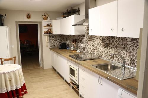 a kitchen with white cabinets and a sink at Casa Labradores Piscina, SPA, Barbacoa y Salon Juegos in Camarenilla
