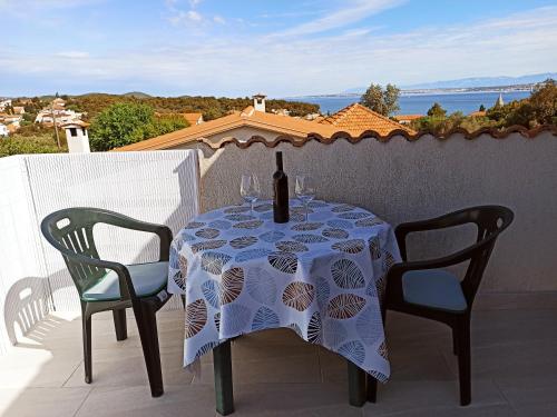 a table with a bottle of wine and two chairs at Apartments Kornati in Ždrelac