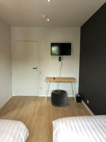a room with two beds and a table and a door at Hotel Le Cygne d'Argent in Liège