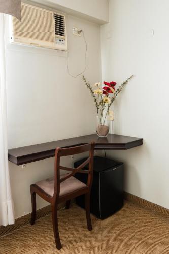 a desk with a chair and a vase with flowers at Hotel Embajador in San Miguel de Tucumán